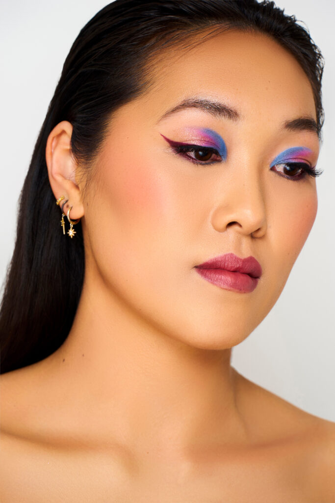 Model met artistieke blauw-paarse oogmake-up en winged eyeliner.