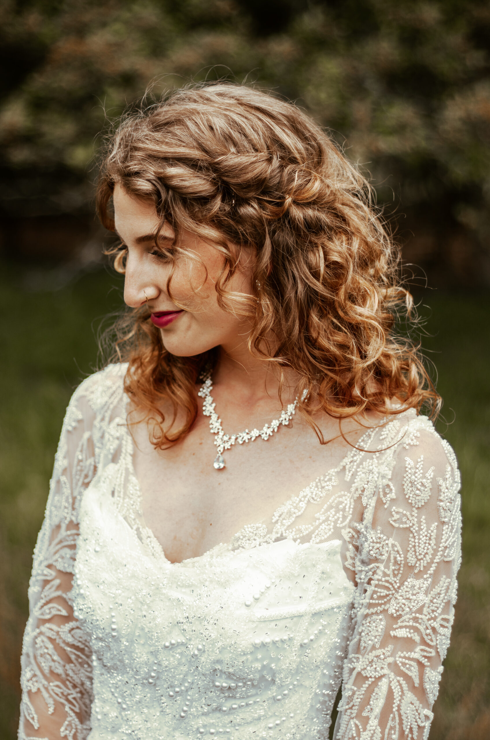 Bruid met een half opgestoken kapsel en natuurlijke krullen, perfect voor een elegante en romantische uitstraling.
